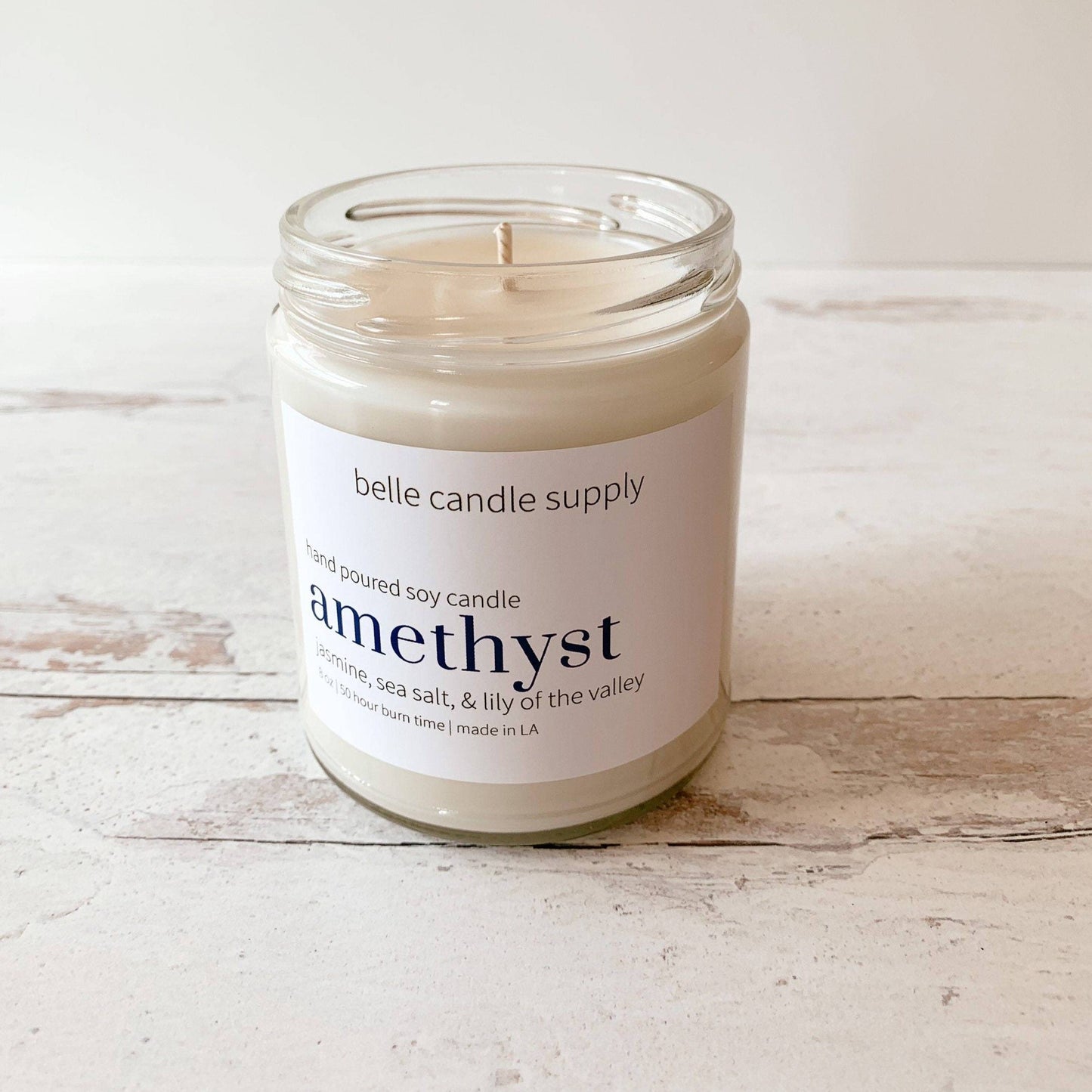 Candle in a glass jar with a label on a wooden surface