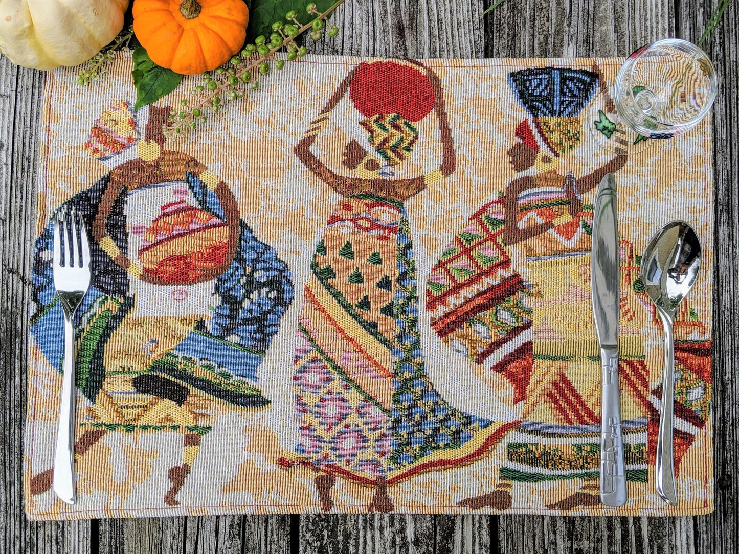 DaDa Bedding Kwanzaa Collection African Dreams placemats on dining table – colorful African women tapestry design in red and ivory tones.
