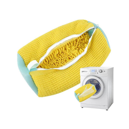 Yellow chenille shoe bag holding a pair of canvas sneakers being put inside washer