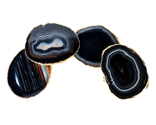 Four large black agate slices with gold edges on a white background