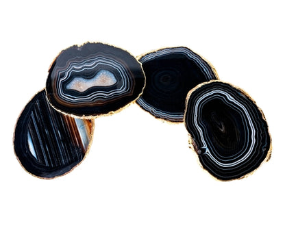 Four large black agate slices with gold edges on a white background