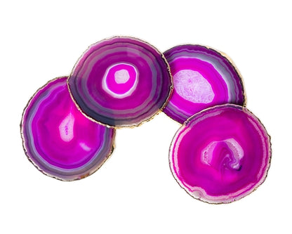 Four pink agate coasters with gold edges on a white background
