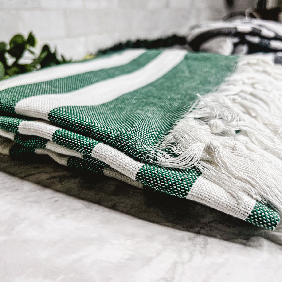 Green striped Bold Turkish towel showing hand-tied tassels