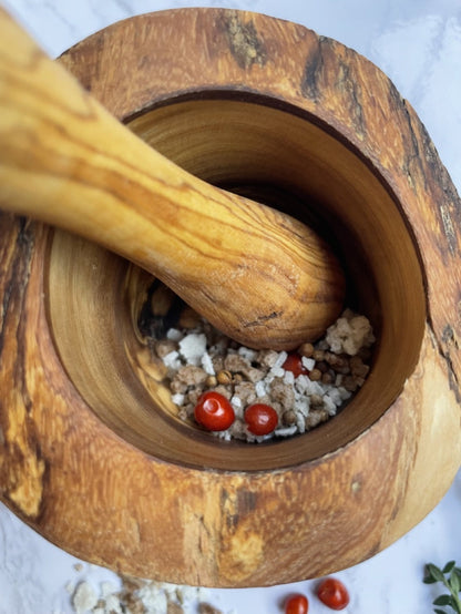 “Close-up of rustic olive wood mortar being used to grind herbs, highlighting durability and artisan craftsmanship.”