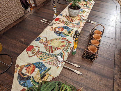 Diagonal view of Kwanzaa Collection African Dreams woven table runner with tribal art and burgundy tassels, styled with dining décor.