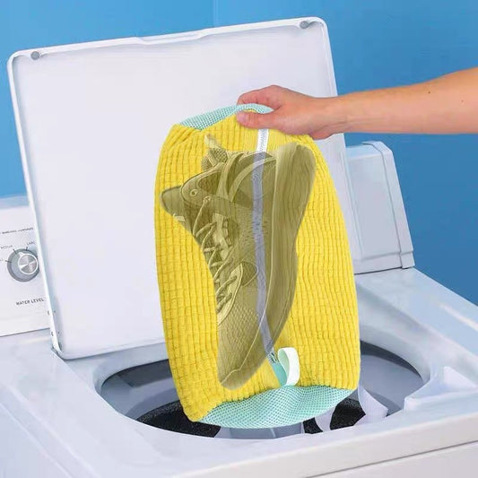 User placing sneakers into white chenille wash bag before washing