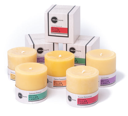 Set of yellow pillar candles with labeled containers and a white box in the background.