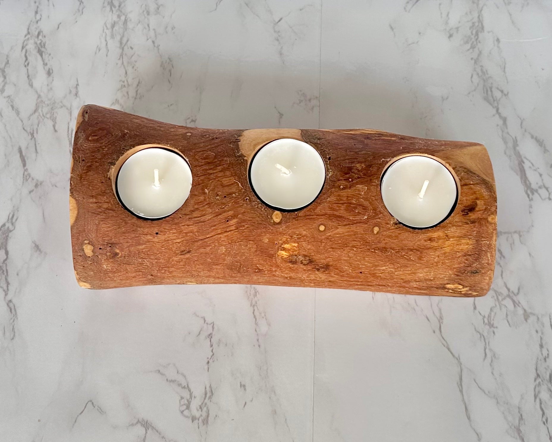 “Three-candle olive wood holder adding cozy, rustic charm to a living space.”