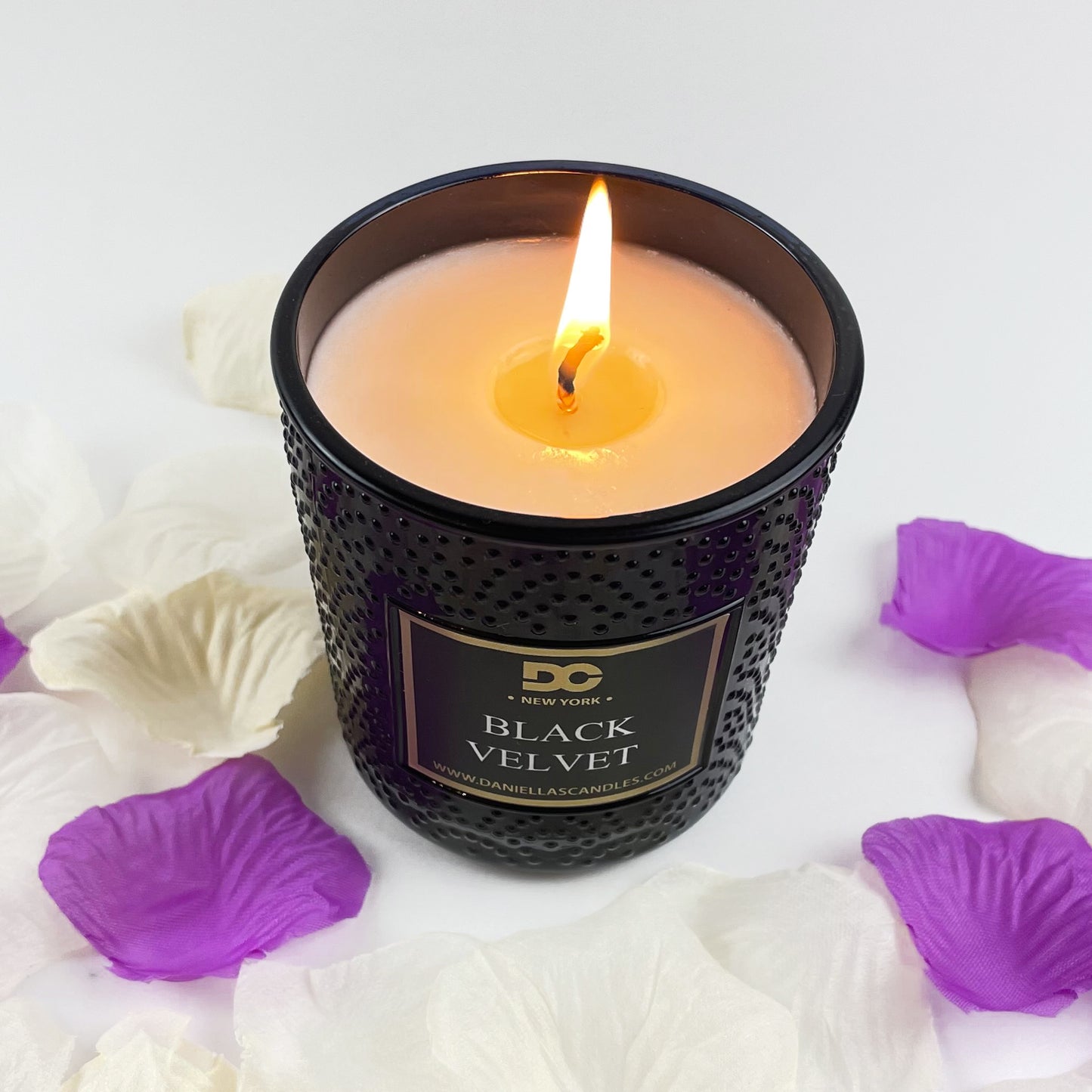 Black Velvet candle with purple and white petals on a light background