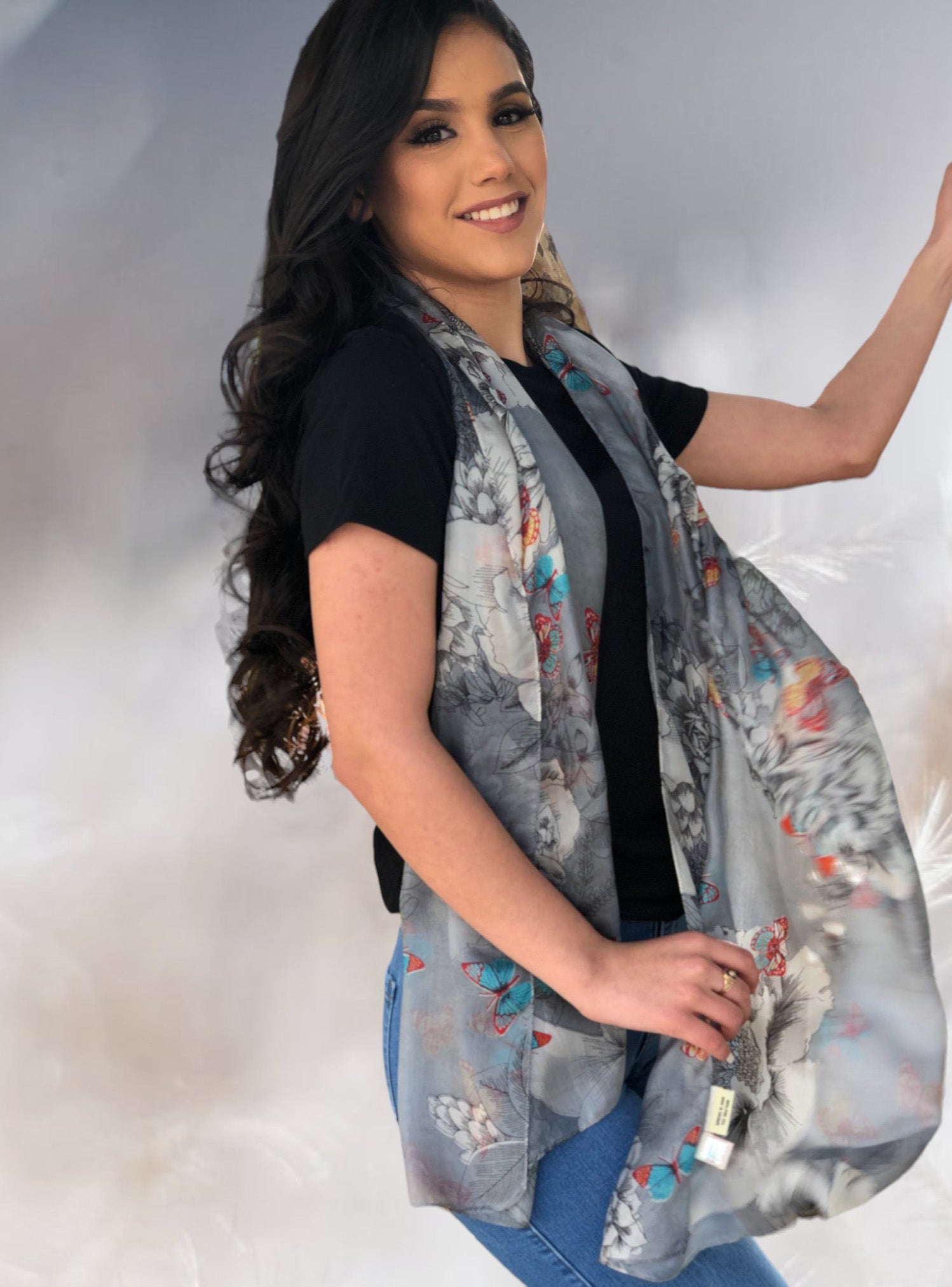 Woman wearing a grey, floral, silk scarf on a plain background