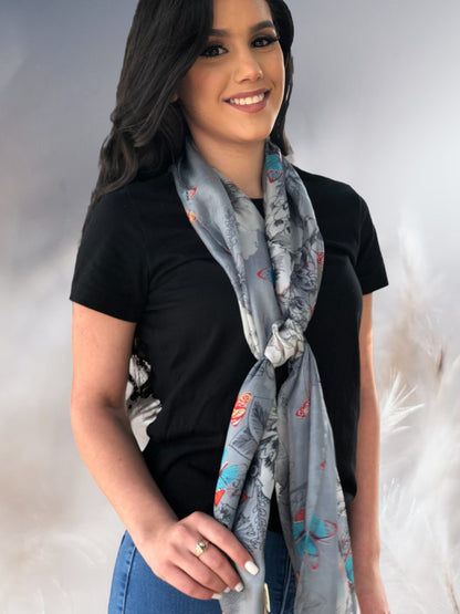 Woman wearing a black top and a patterned grey, silk scarf against a neutral background