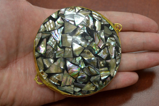 Round decorative item with shell inlay held in a hand
