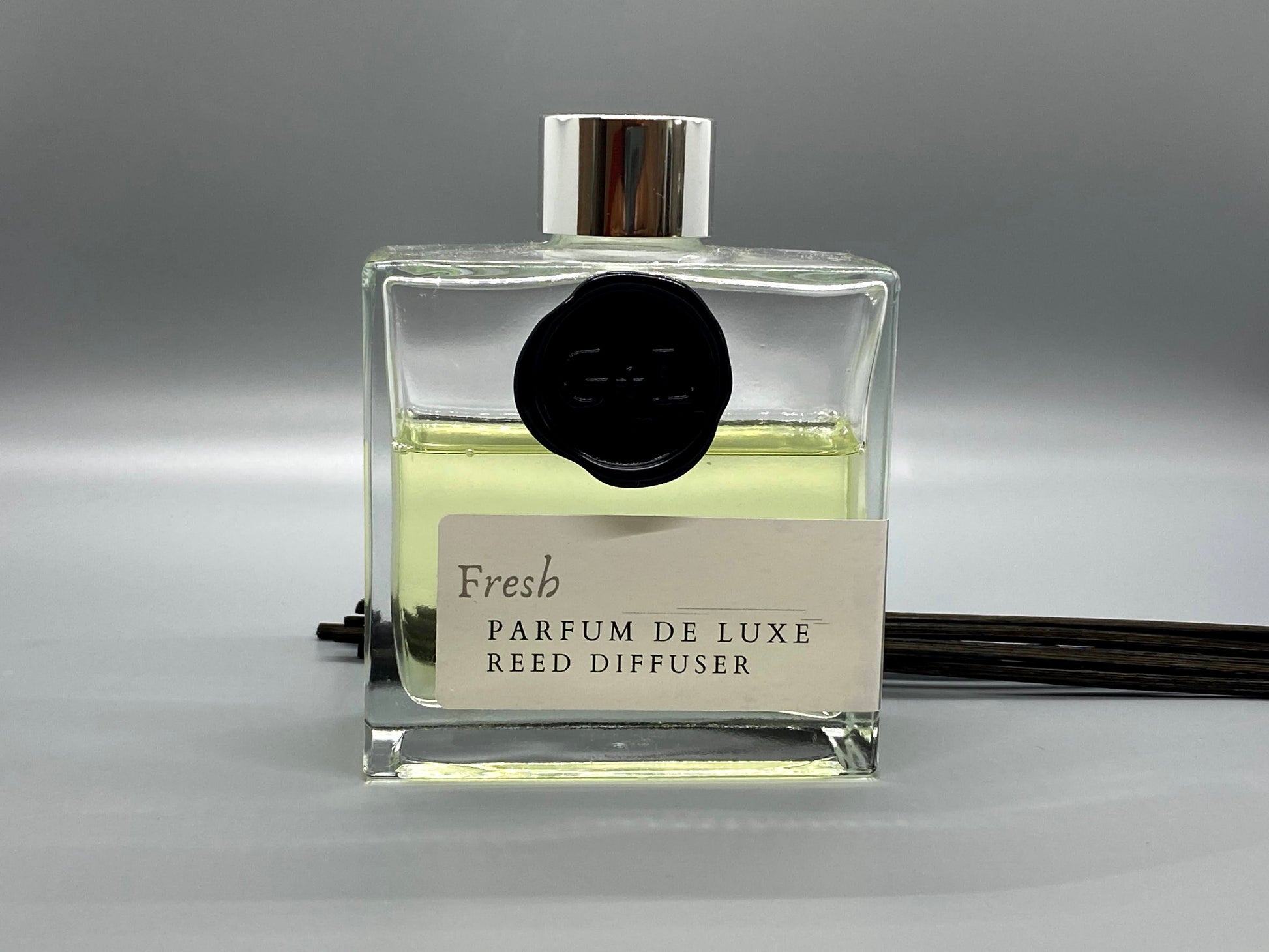 Reed diffuser bottle labeled 'Fresh Parfum de Luxe' on a gray background