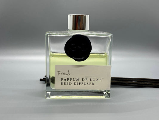 Reed diffuser bottle labeled 'Fresh Parfum de Luxe' on a gray background