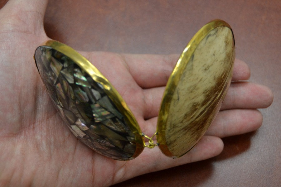 Two gold compact mirrors held in a hand against a brown background