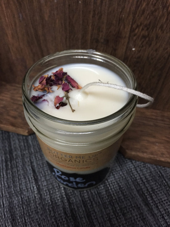 Candle in a glass jar with dried flowers on a wooden surface
