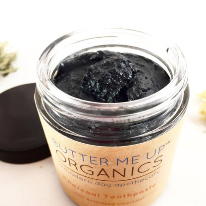 Open jar of charcoal toothpaste showing natural black texture.