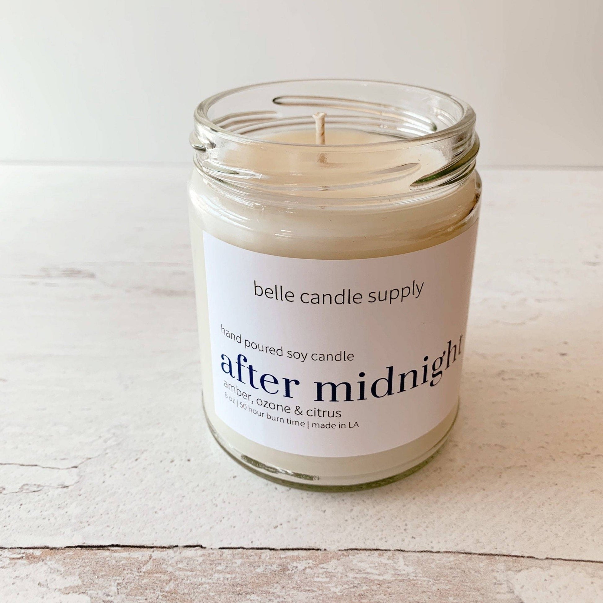 Candle in a glass jar with a label on a wooden surface
