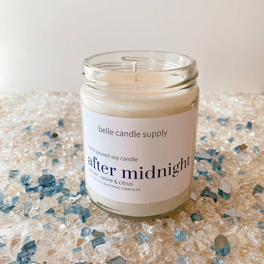 Candle in a glass jar with a label on a textured surface