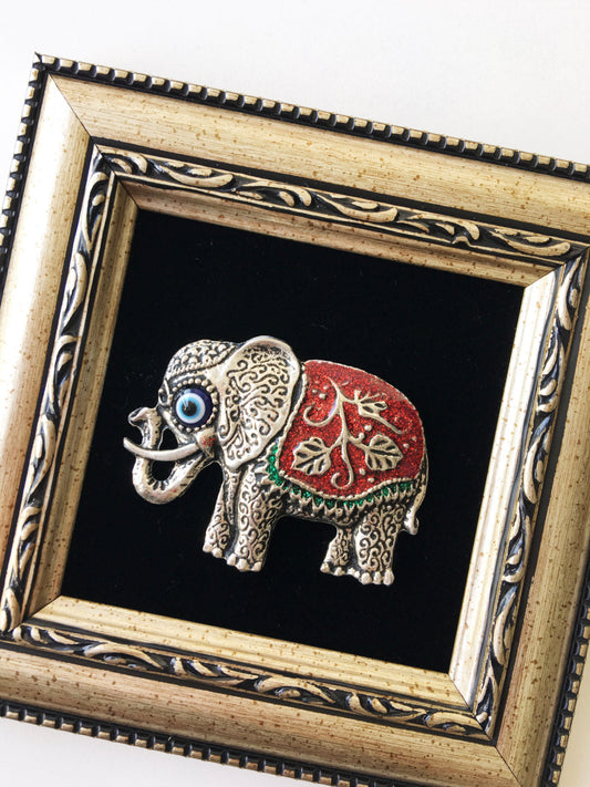 Close-up of red elephant and evil eye charm handmade wall art in frame