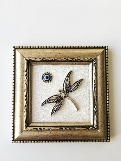 Close-up of silver dragonfly and evil eye bead.