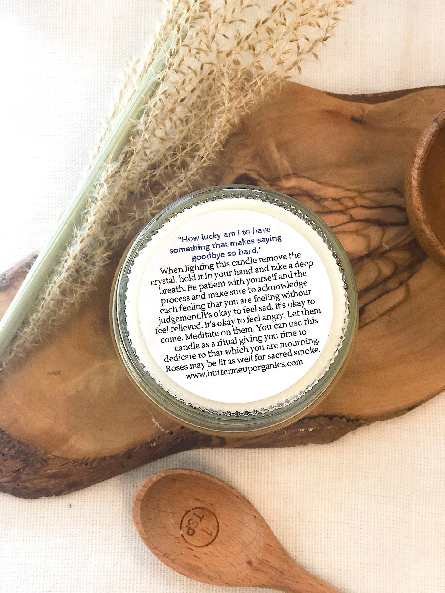 Krombee Remembrance Candle Jar with a label on a wooden surface with a spoon and crystal