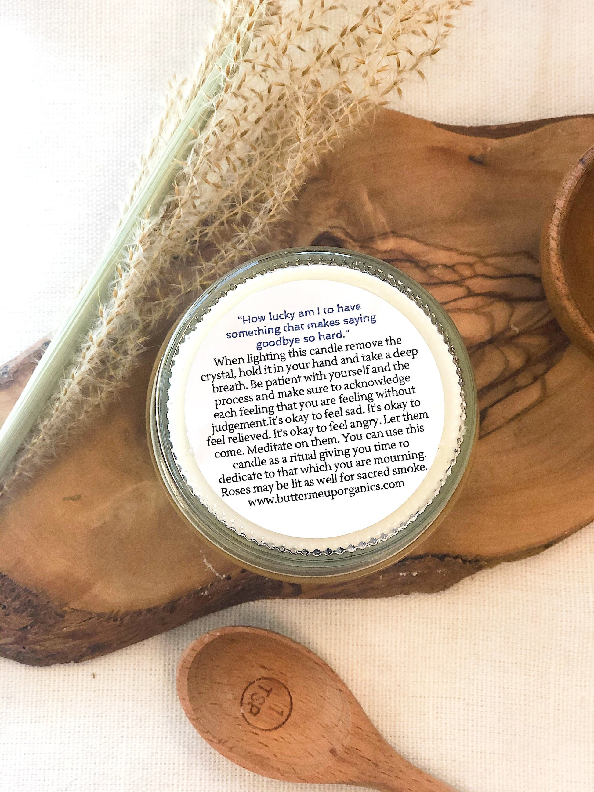 Krombee Remembrance Candle Jar with a label on a wooden surface with a spoon and crystal
